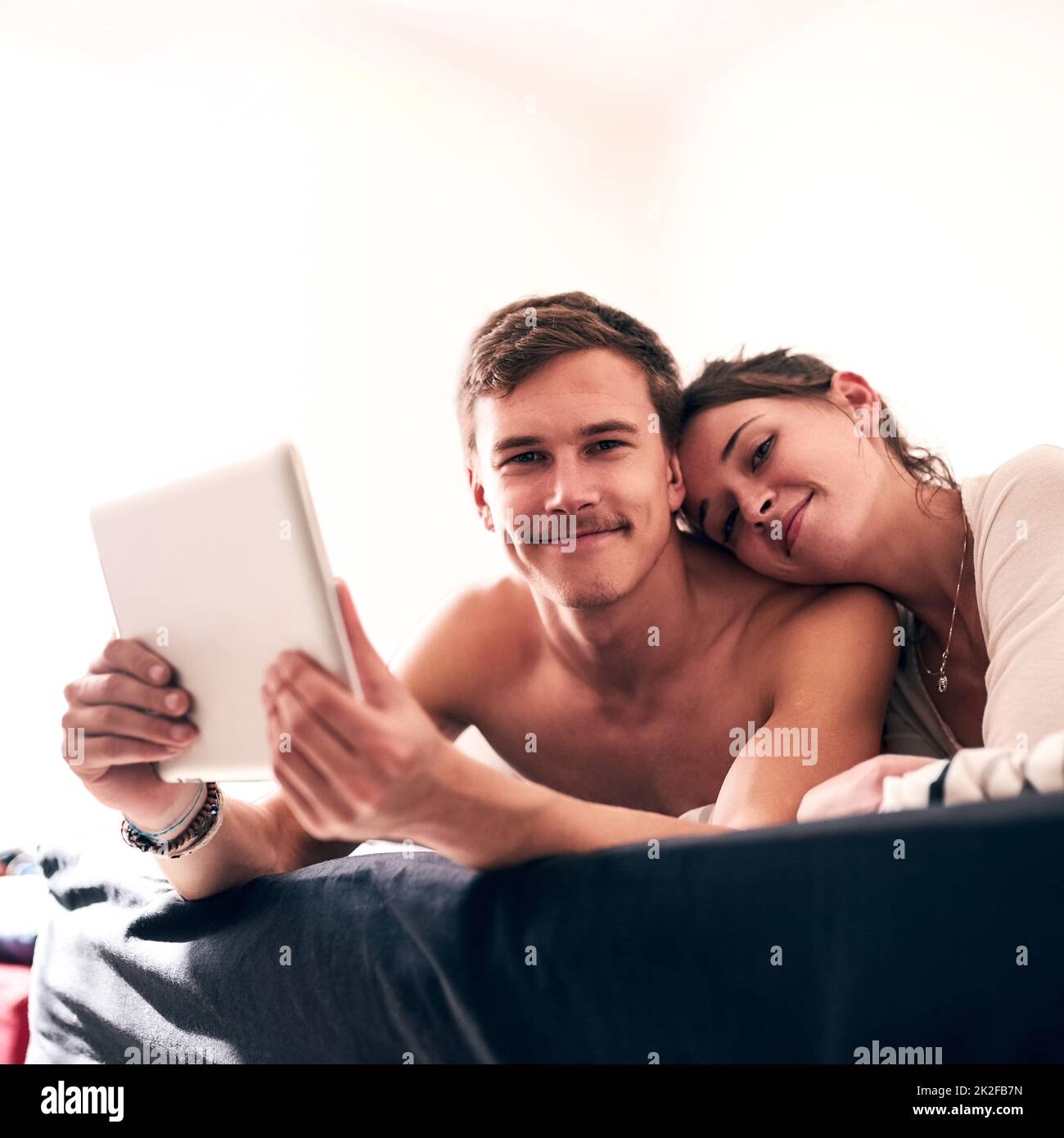 Weve ha una forte connessione. Ritratto di una giovane coppia che trascorre una giornata pigra a letto con il tablet. Foto Stock