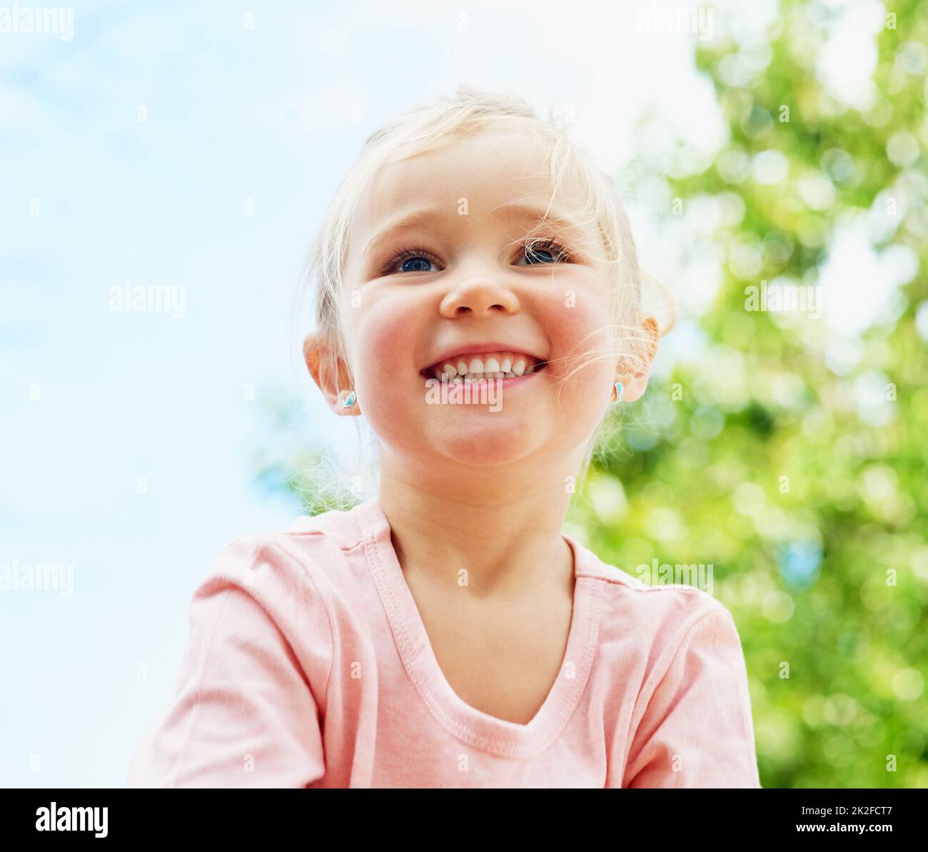 Divertimento sotto il sole estivo. Scatto di una ragazza piccola carina sorridente mentre gioca all'esterno. Foto Stock
