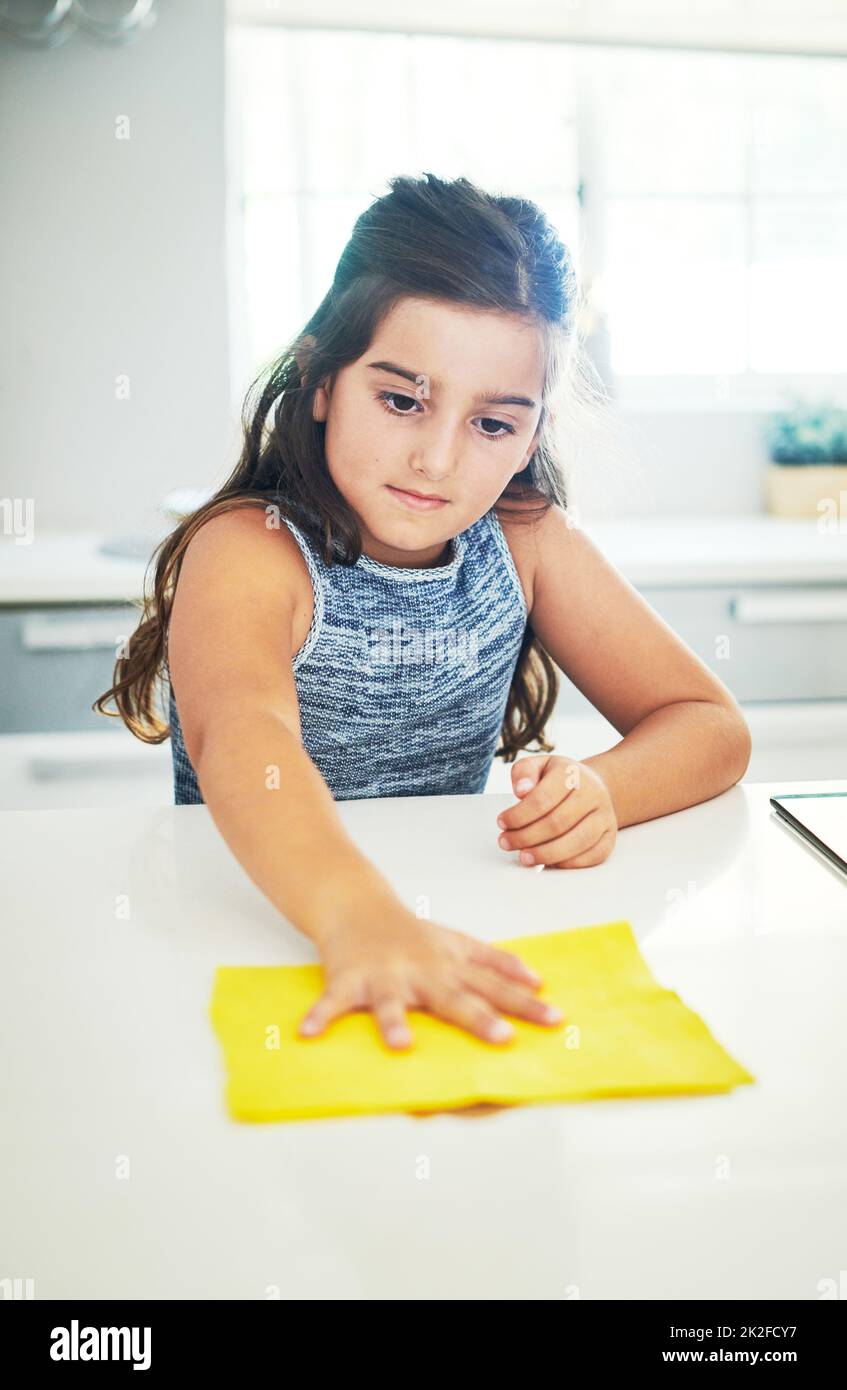 Questo è il modo in cui la mamma lo fa. Scatto di una ragazza piccola adorabile che aiuta fuori con i chores a casa. Foto Stock