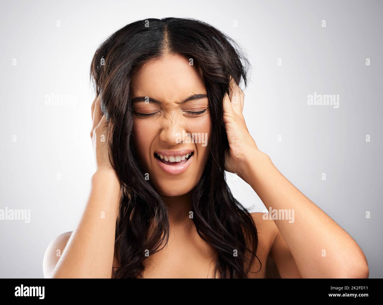 Ceneri pazzi sui capelli. Scatto ritagliato di una giovane donna attraente in posa in studio su uno sfondo grigio. Foto Stock