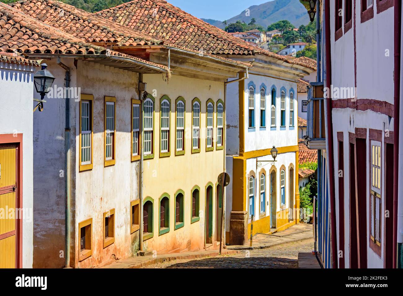 Strada tranquilla con vecchie case colorate in architettura coloniale, ciottoli e lanterne Foto Stock