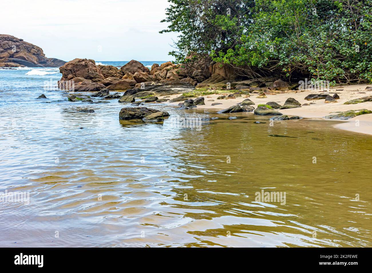 Acque di un piccolo fiume che si dirige verso il mare tra la sabbia e la foresta di Trindade Foto Stock
