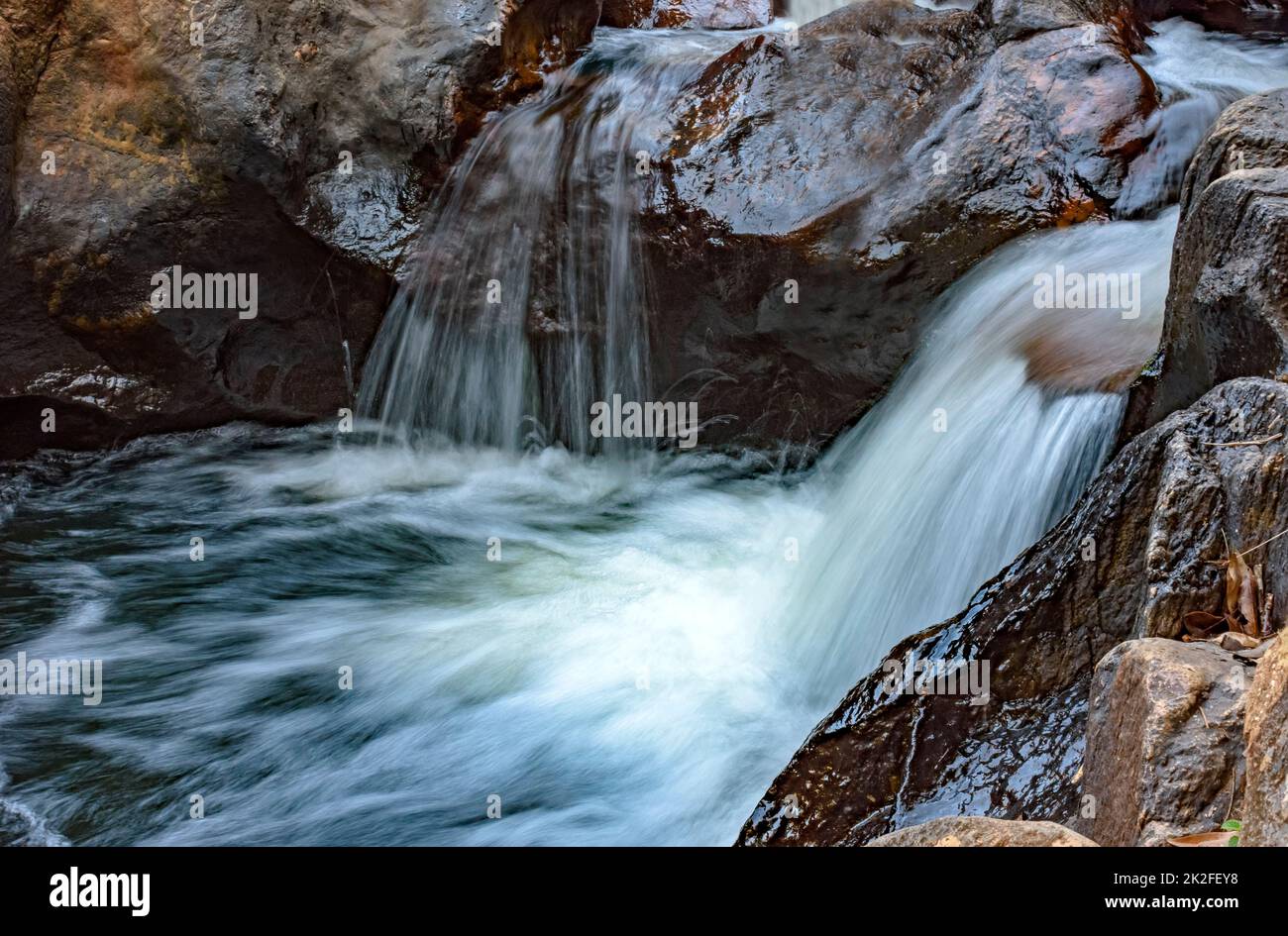 Piccolo fiume con acque limpide e cascata che attraversa le rocce Foto Stock