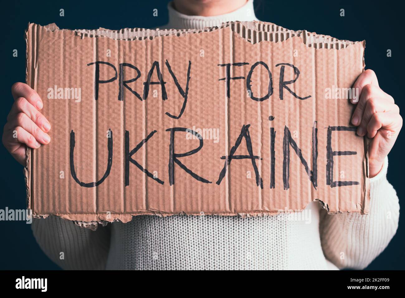 Primo piano sulla mano della donna con la bandiera di preghiera per l'Ucraina Foto Stock