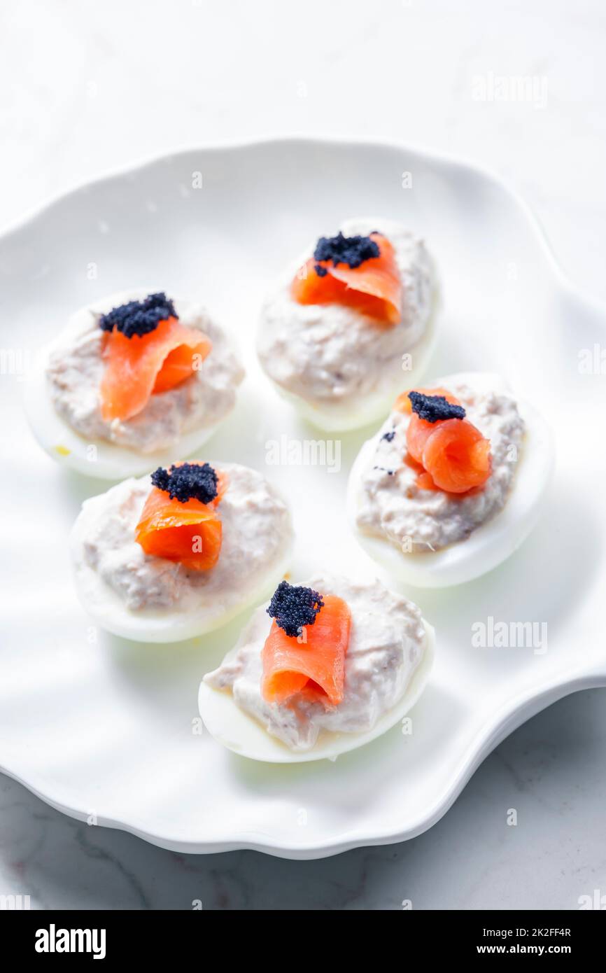 uova sode ripieni di tonno sparso e salmone affumicato e caviale nero sulla parte superiore Foto Stock