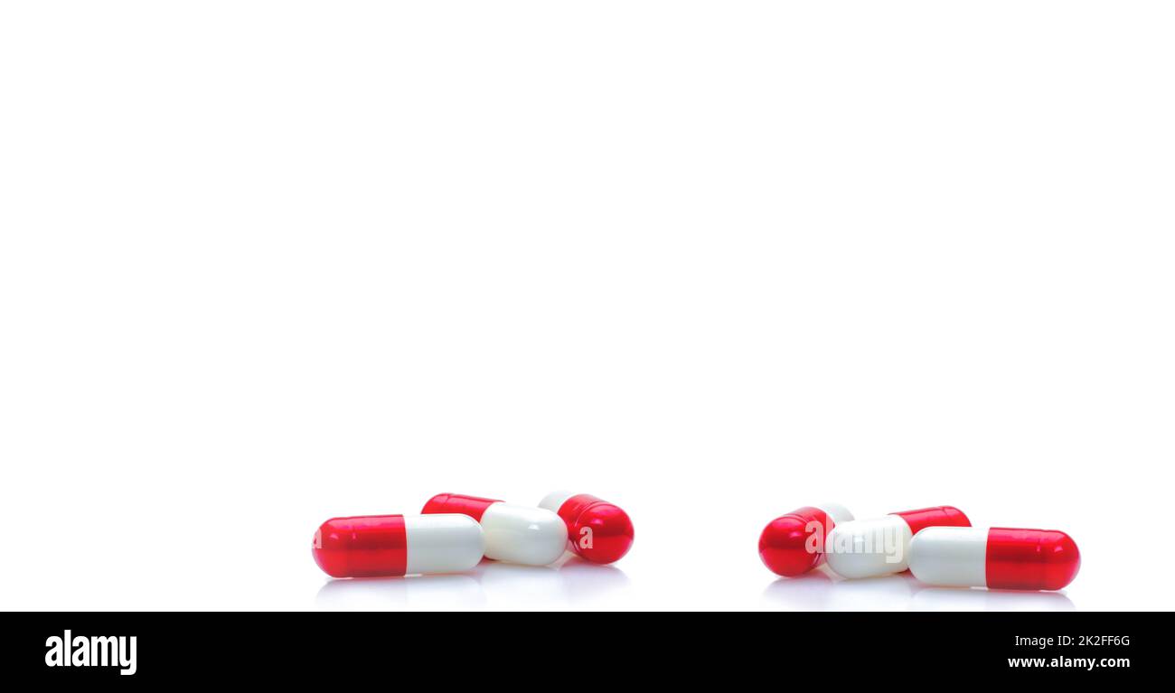 Gruppo di capsule rosse-bianche su fondo bianco orizzontale. Farmaci da prescrizione. Banner web farmacia. Assistenza sanitaria e background medico. Produzione di droga. Dose giornaliera per il richiamo dell'amore. Foto Stock