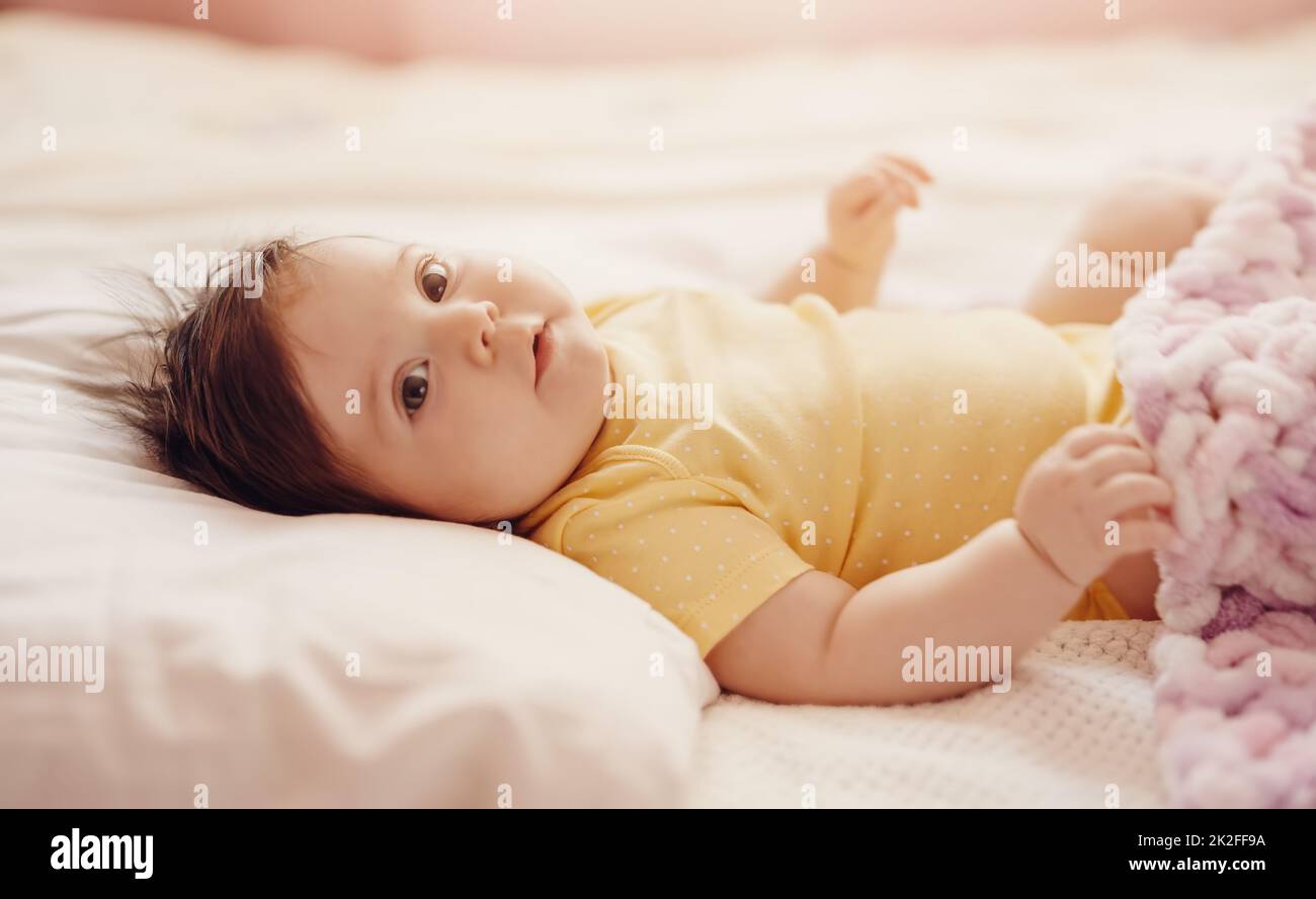 Bambino piccolo carino sdraiato sotto coperta rosa. Foto Stock