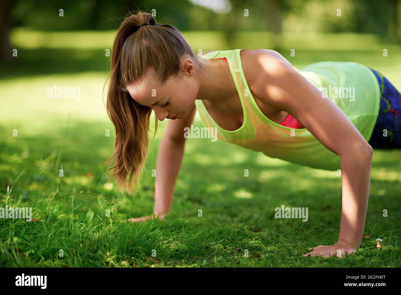 Dedicatevi. Girato di una giovane donna che fa push-up su un campo erboso. Foto Stock