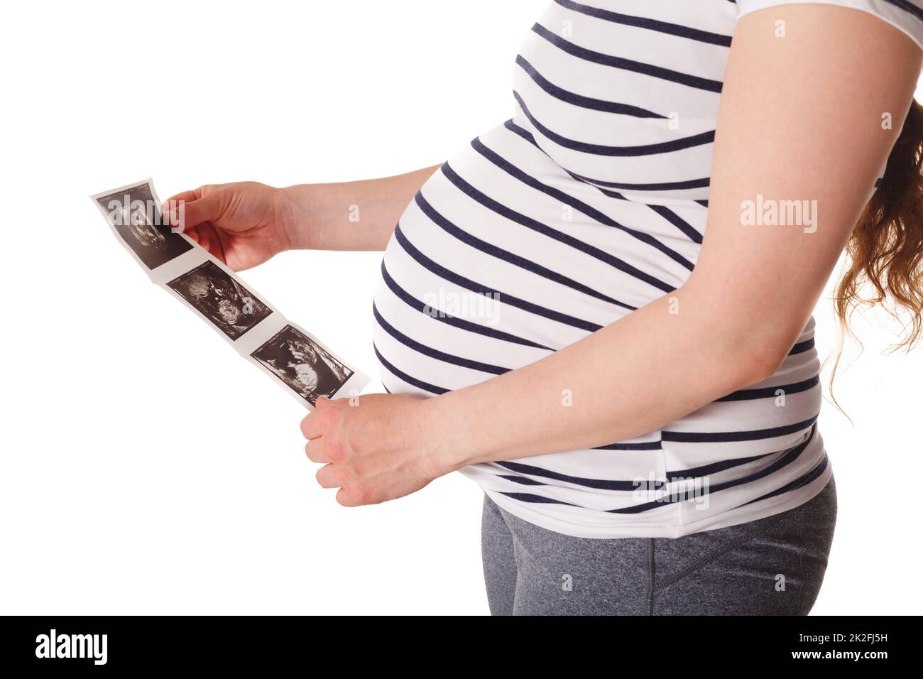 Donna incinta in piedi e tenendo la sua scansione del bambino a ultrasuoni Foto Stock