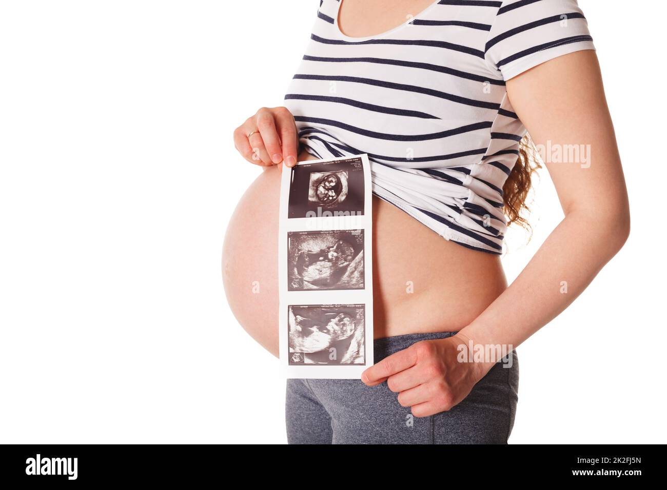 Donna incinta in piedi e tenendo la sua scansione del bambino a ultrasuoni Foto Stock