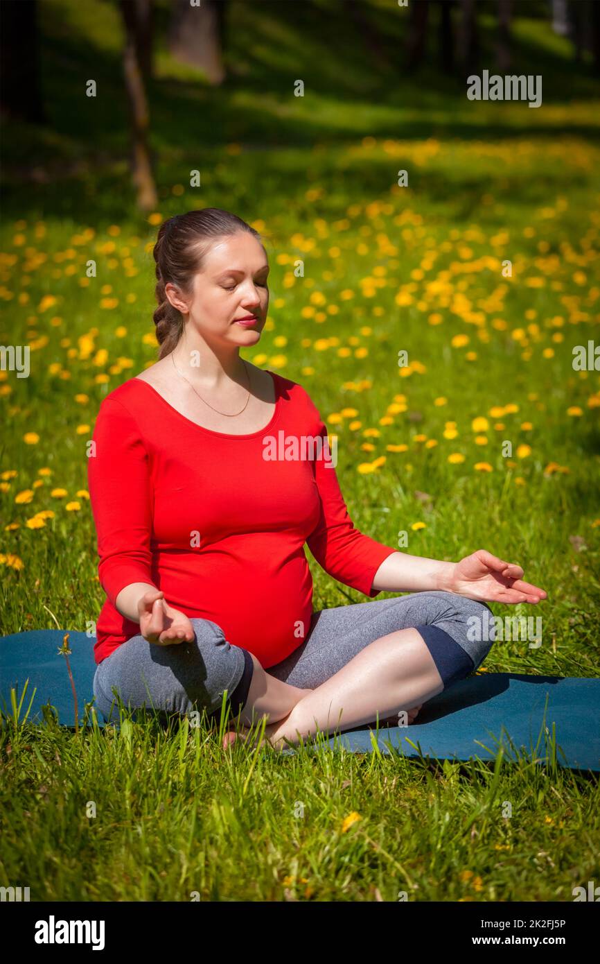 Donna incinta che fa asana Sukhasana all'aperto Foto Stock