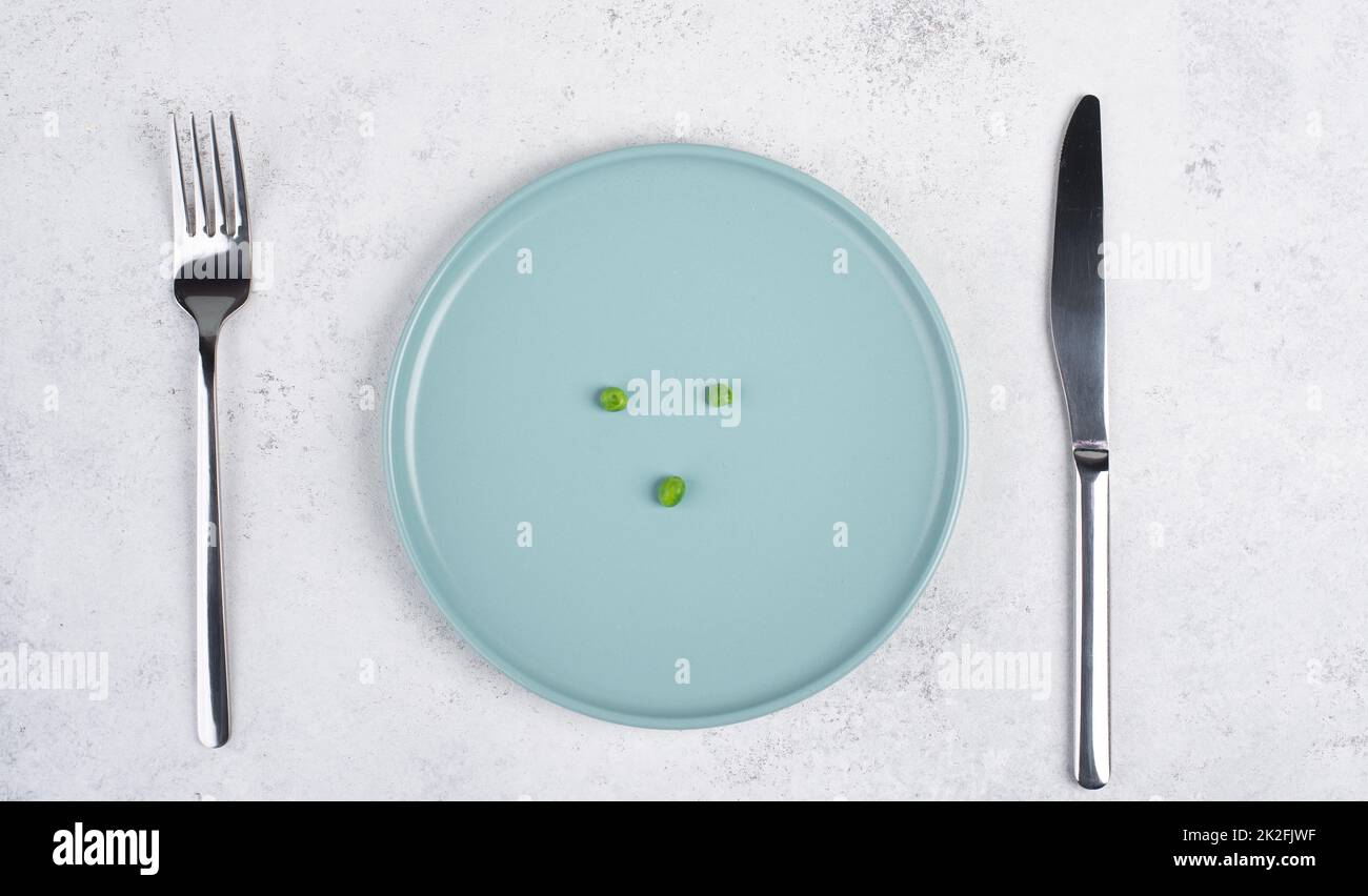 Tre piselli verdi su un piatto, forchetta e coltello sul tavolo, dieta e  perdere il concetto di peso, stile di vita sano Foto stock - Alamy