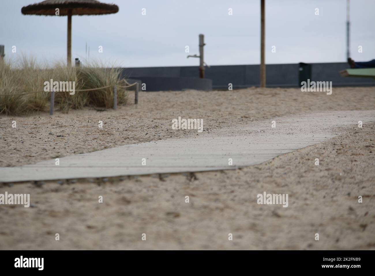 Primo piano di una spiaggia di sabbia con un sentiero in legno in una giornata fredda Foto Stock
