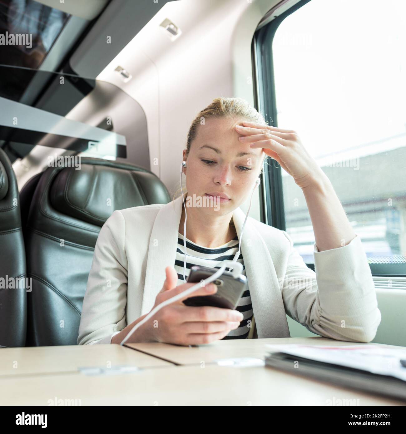 Imprenditrice comunicanti sul telefono cellulare mentre si è in viaggio in treno. Foto Stock