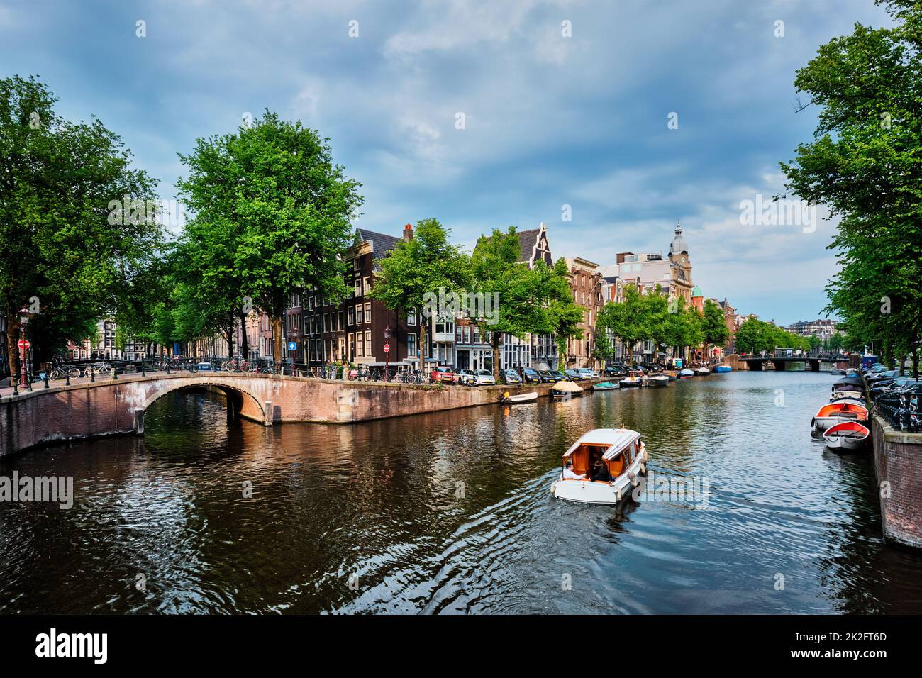 Vista su Amsterdam - canale con boad, ponte e vecchie case Foto Stock