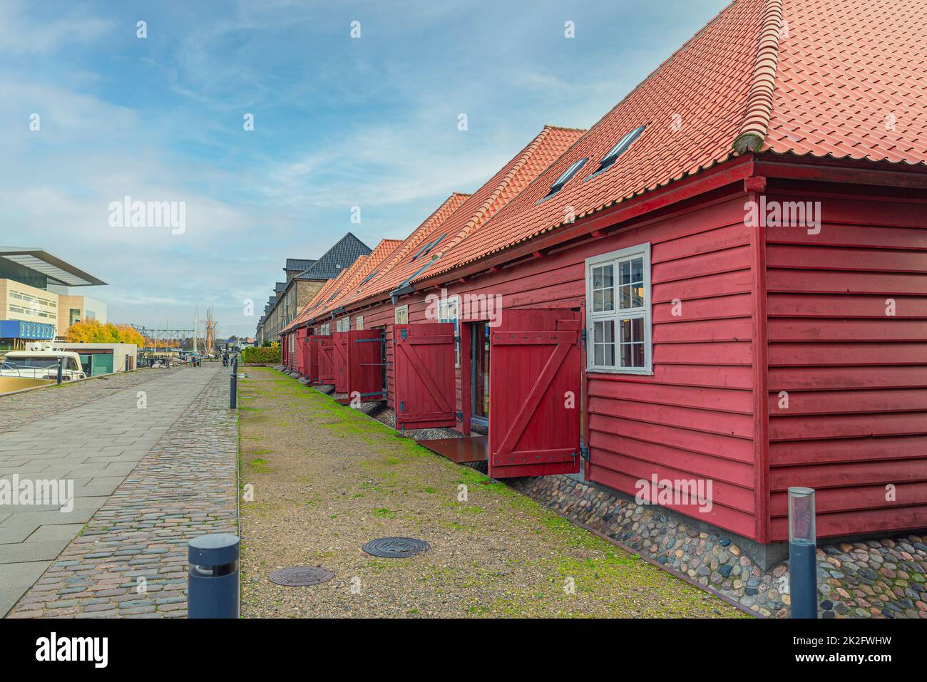 Case di legno rosso a un piano con uffici e negozi sull'isola del quartiere Christianshavn vicino al teatro dell'opera di Copenhagen. Danimarca Foto Stock