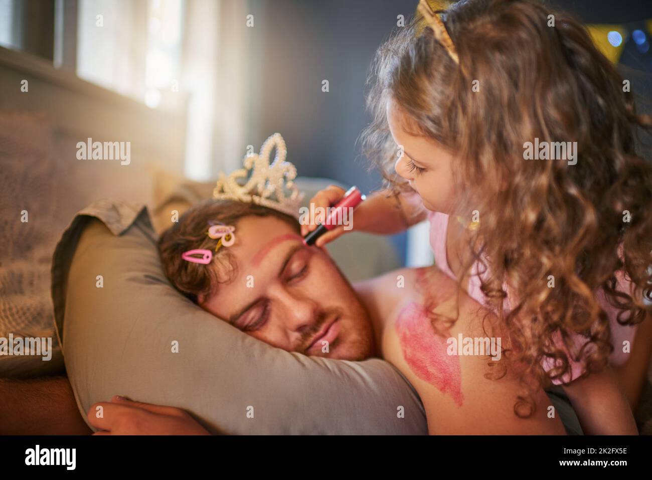 Penso che papà potrebbe fare con un makeover. Scatto di una bambina adorabile che disegnava con rossetto sul volto dei padri mentre dorme. Foto Stock