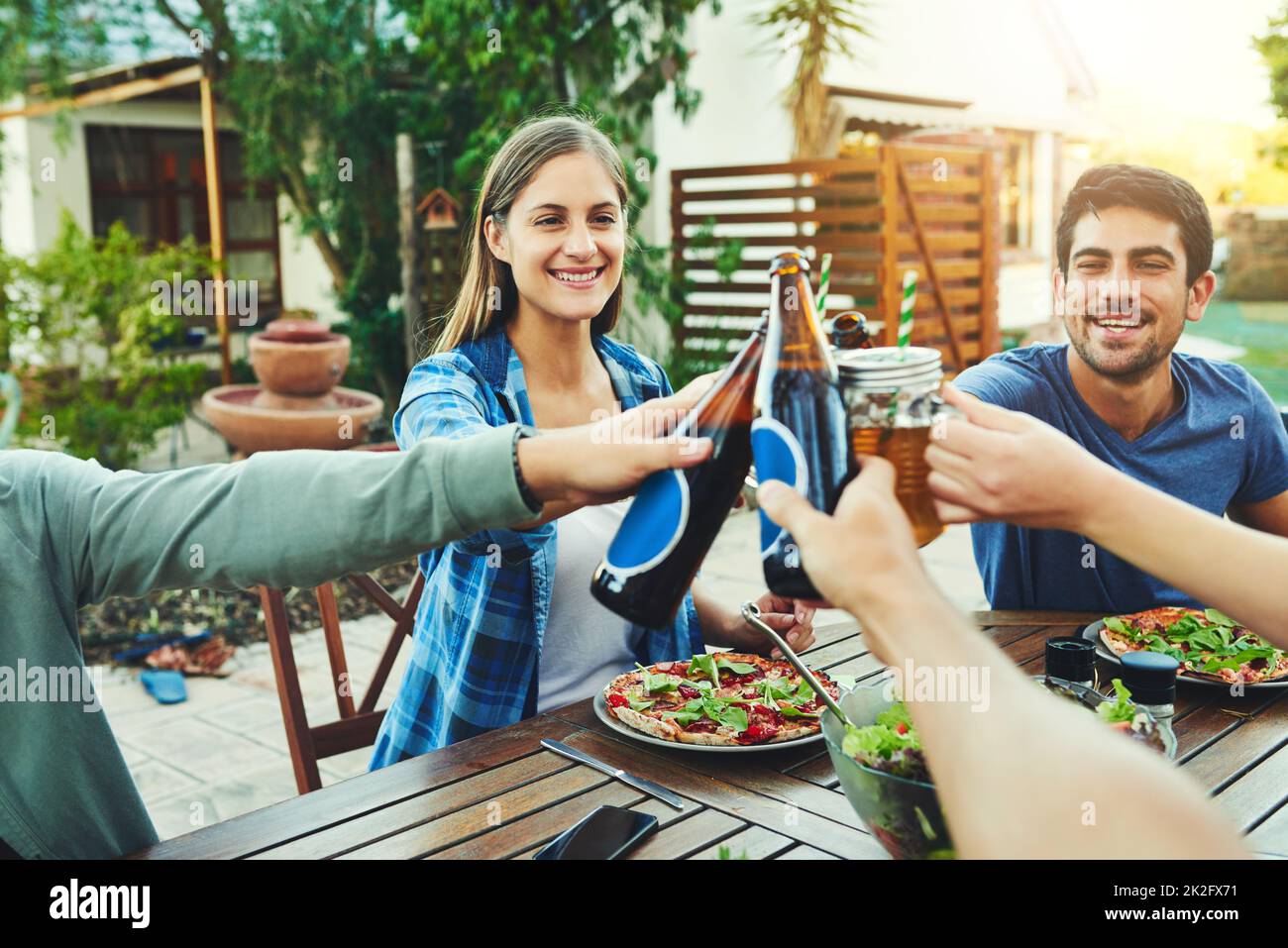 Celebrate la vita con coloro che apprezzate di più. Foto di un gruppo di giovani amici che sorreggono un drink e brindano per celebrare la loro amicizia intorno a un tavolo all'aperto. Foto Stock