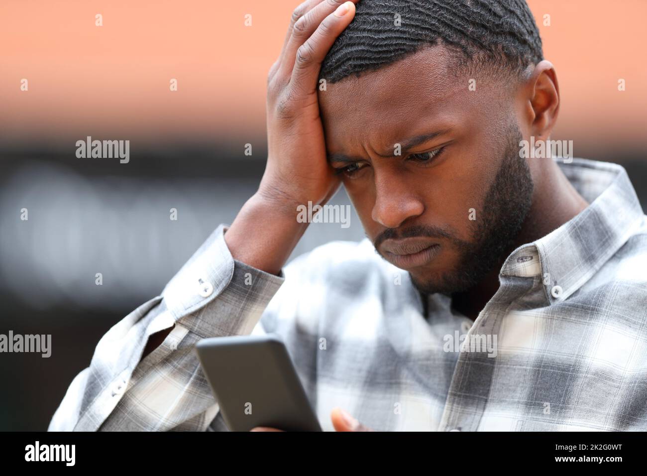 Uomo preoccupato con pelle nera che lamenta il controllo del telefono Foto Stock