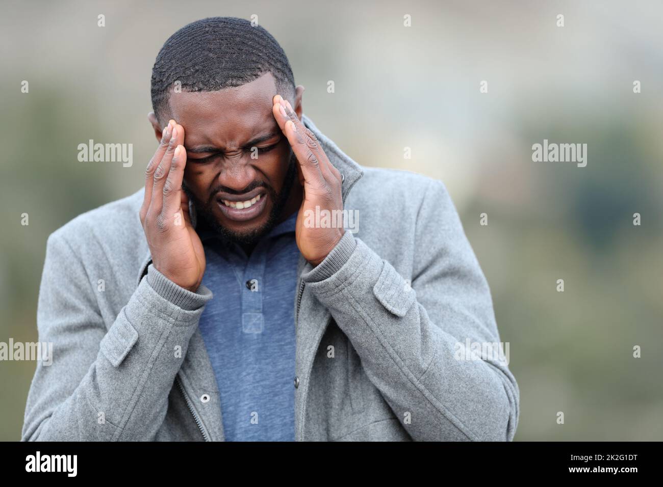 Uomo stressato con pelle nera che soffre emicrania in inverno Foto Stock