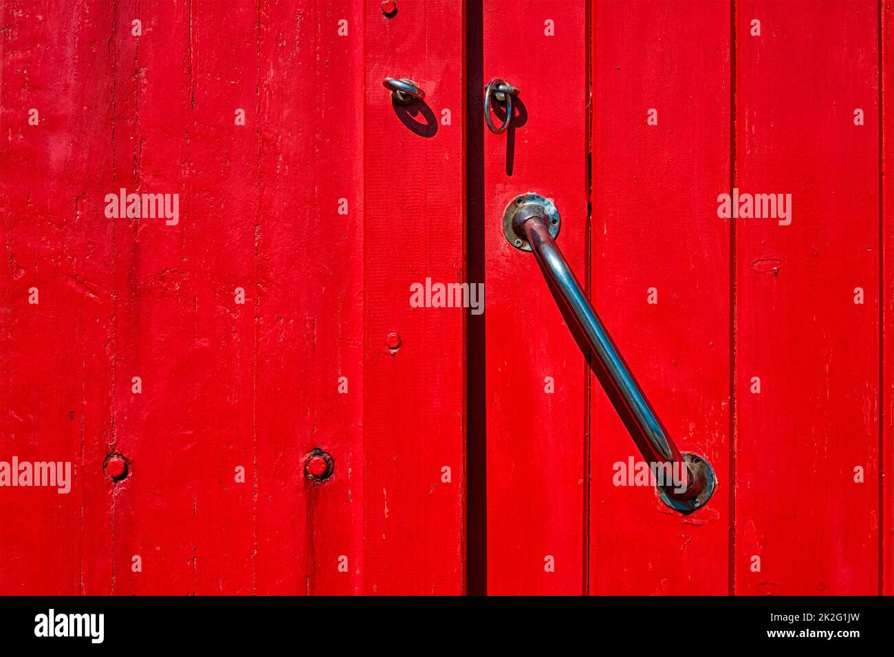 Porta in legno rosso verniciato con maniglia della porta Foto Stock