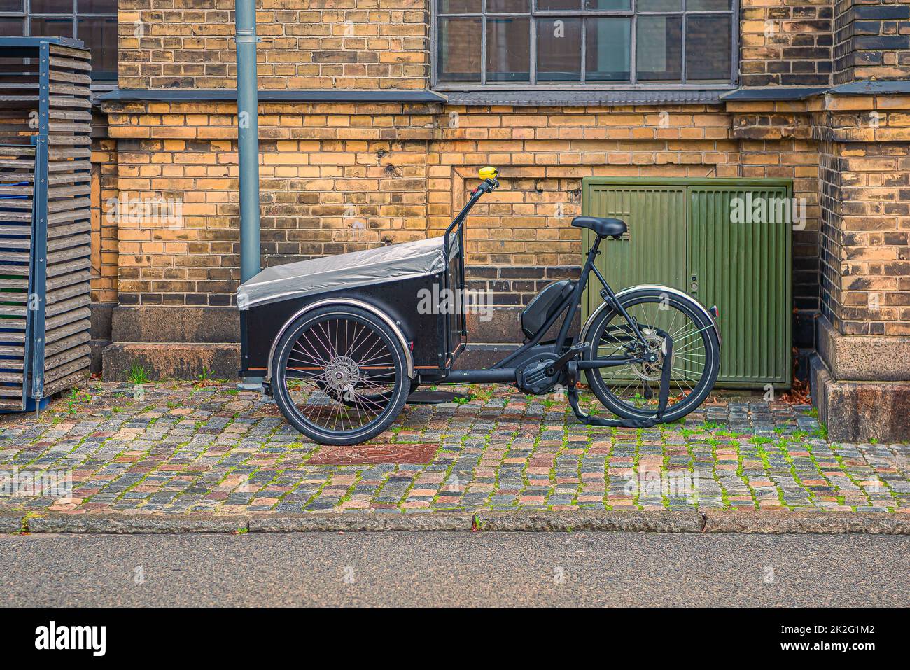 Una bicicletta di famiglia del carico del triciclo con la scatola per il trasporto dei bambini si trova su una strada nella città vecchia. Copenaghen, Danimarca Foto Stock