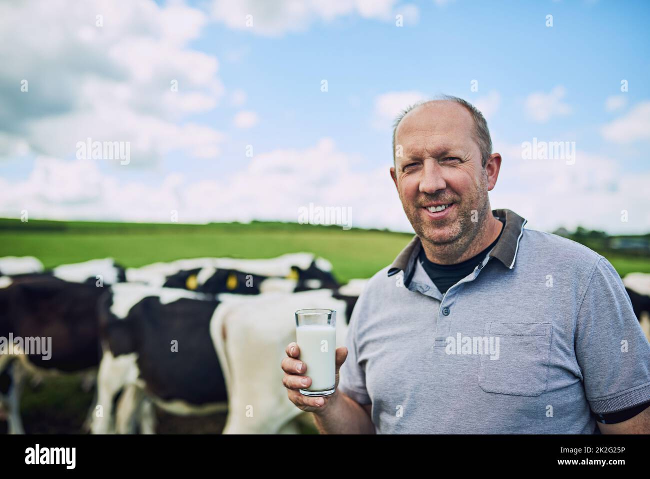 È solo il migliore della mia fattoria. Ritratto corto di un agricoltore maschio in piedi con un bicchiere di latte nella sua fattoria casearia. Foto Stock