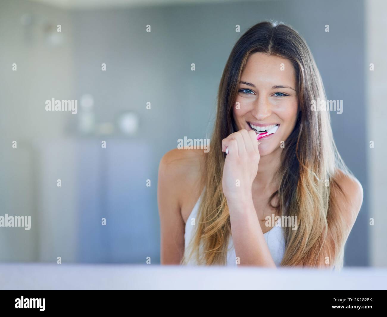 Sempre fresco. Ritratto di una giovane donna felice spazzolando i denti nel suo bagno a casa. Foto Stock