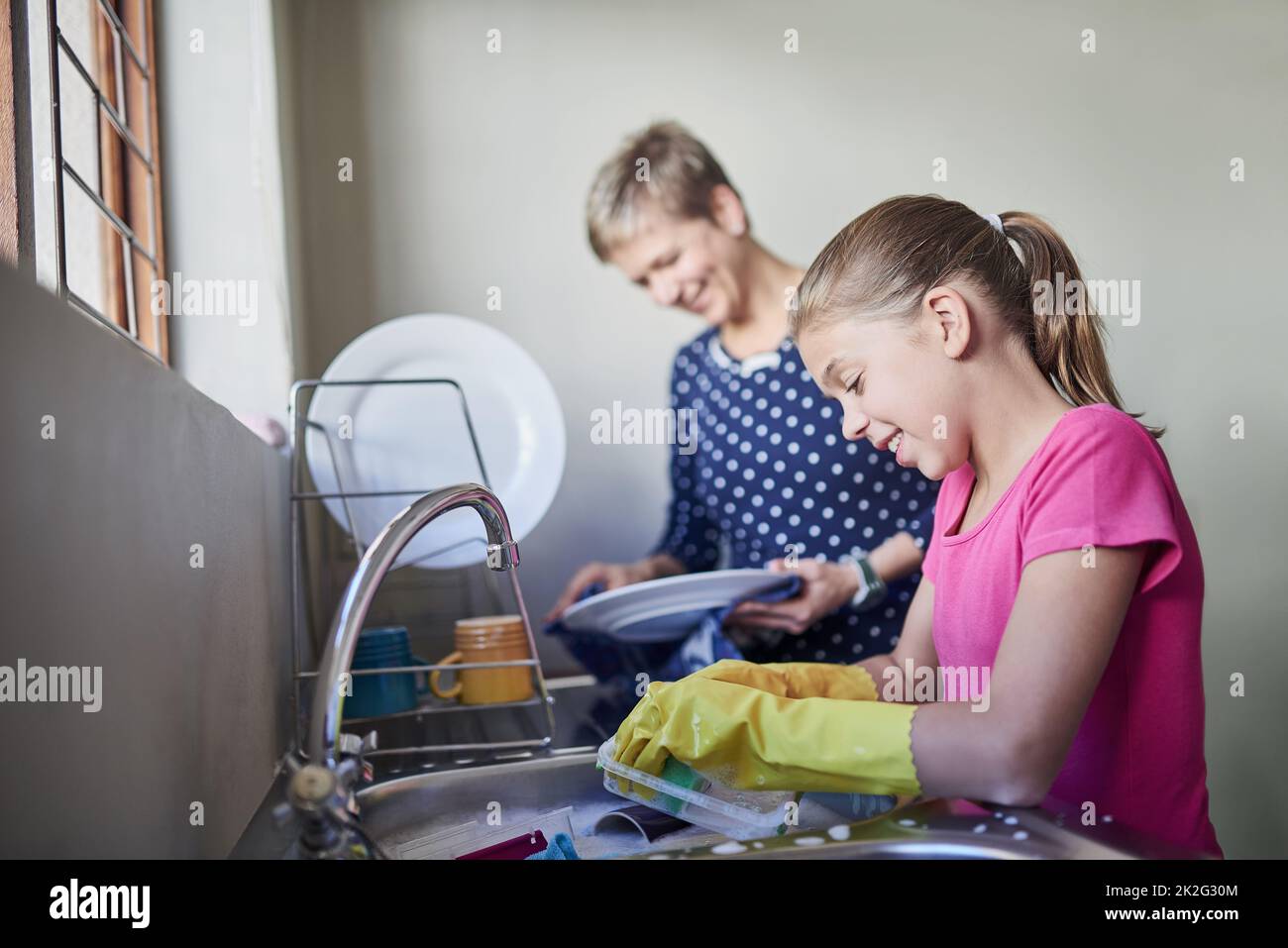 Strofinare fino a quando non è pulitissimo. Shot di una madre e una figlia pulizia piatti insieme. Foto Stock