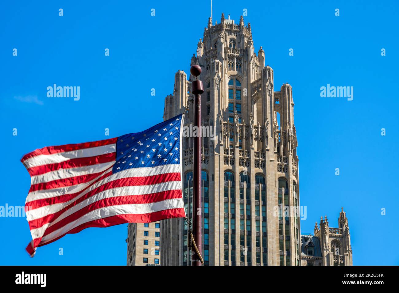 Sventolando la bandiera degli Stati Uniti con Tribune Tower dietro, Chicago, Illinois, USA Foto Stock