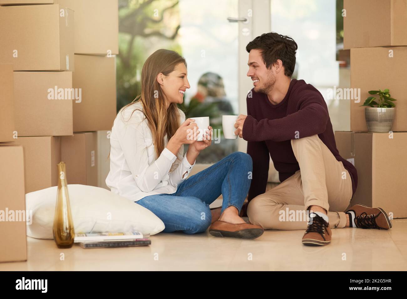 Sedendosi dentro in giorno commovente. Shot di una giovane coppia affettuosa che prende una pausa caffè mentre si sposta in una nuova casa. Foto Stock