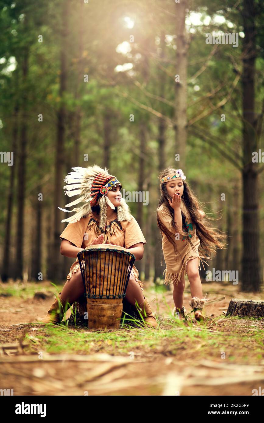 Divertirsi nella natura. Colpo di una giovane donna che batte un tamburo mentre gioca dressup con la figlia nei boschi. Foto Stock