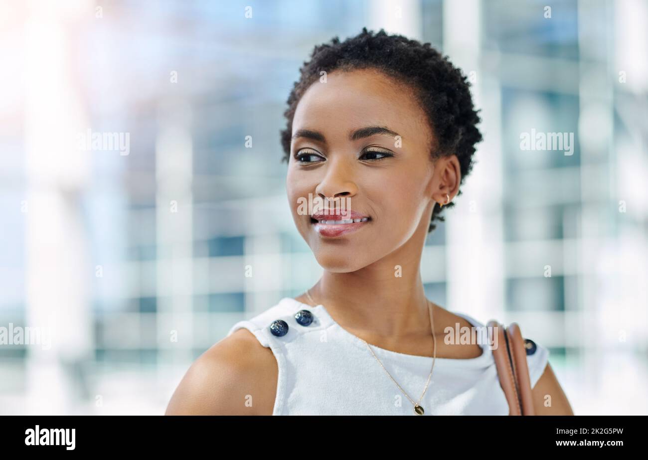 Ive solo appena iniziato.... Scatto corto di una giovane donna d'affari attraente che osserva pensieroso mentre si levano in piedi in un ufficio moderno. Foto Stock