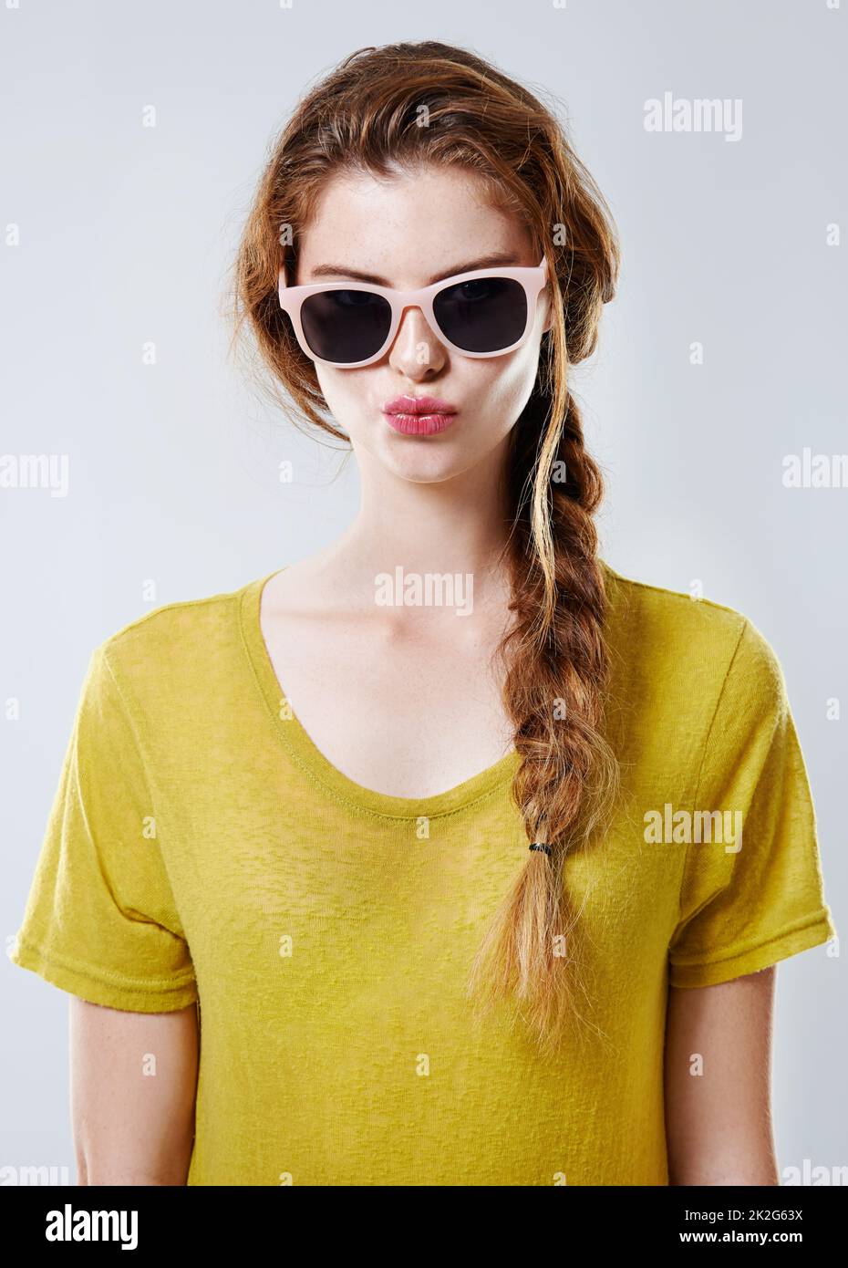 Semplicemente favoloso. Studio ritratto di una giovane donna attraente indossando occhiali da sole alla moda isolato sul grigio. Foto Stock