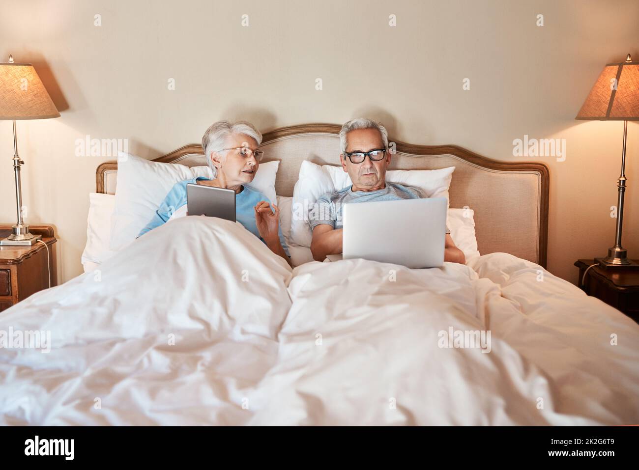Imparare a utilizzare la tecnologia nel 21st ° secolo. Ripresa ritagliata di una coppia anziana seduta a letto insieme e utilizzando la tecnologia in una casa di cura. Foto Stock