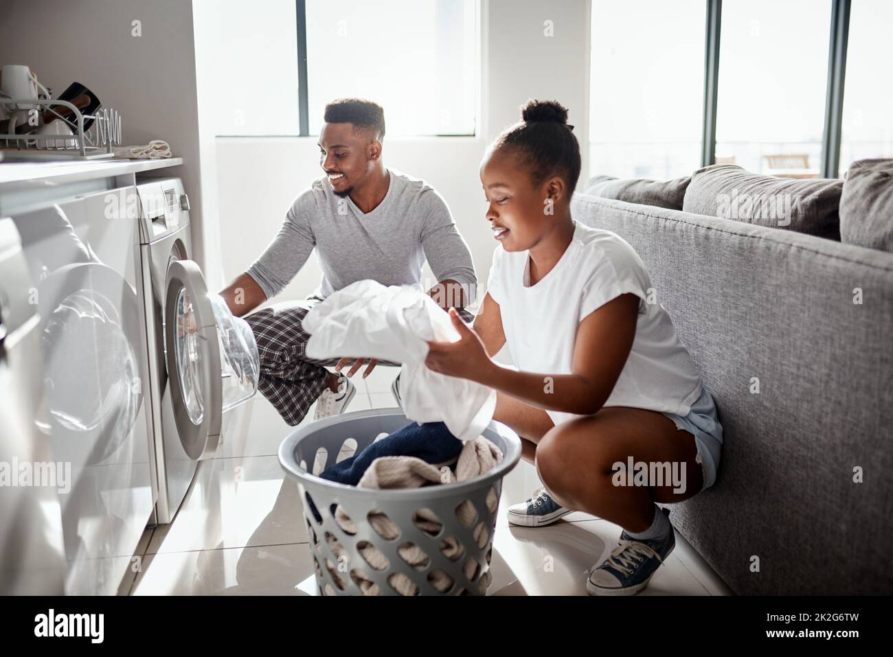 La divisione del lavoro non è solo per il posto di lavoro. Scatto di una giovane coppia felice che fa il bucato insieme a casa. Foto Stock
