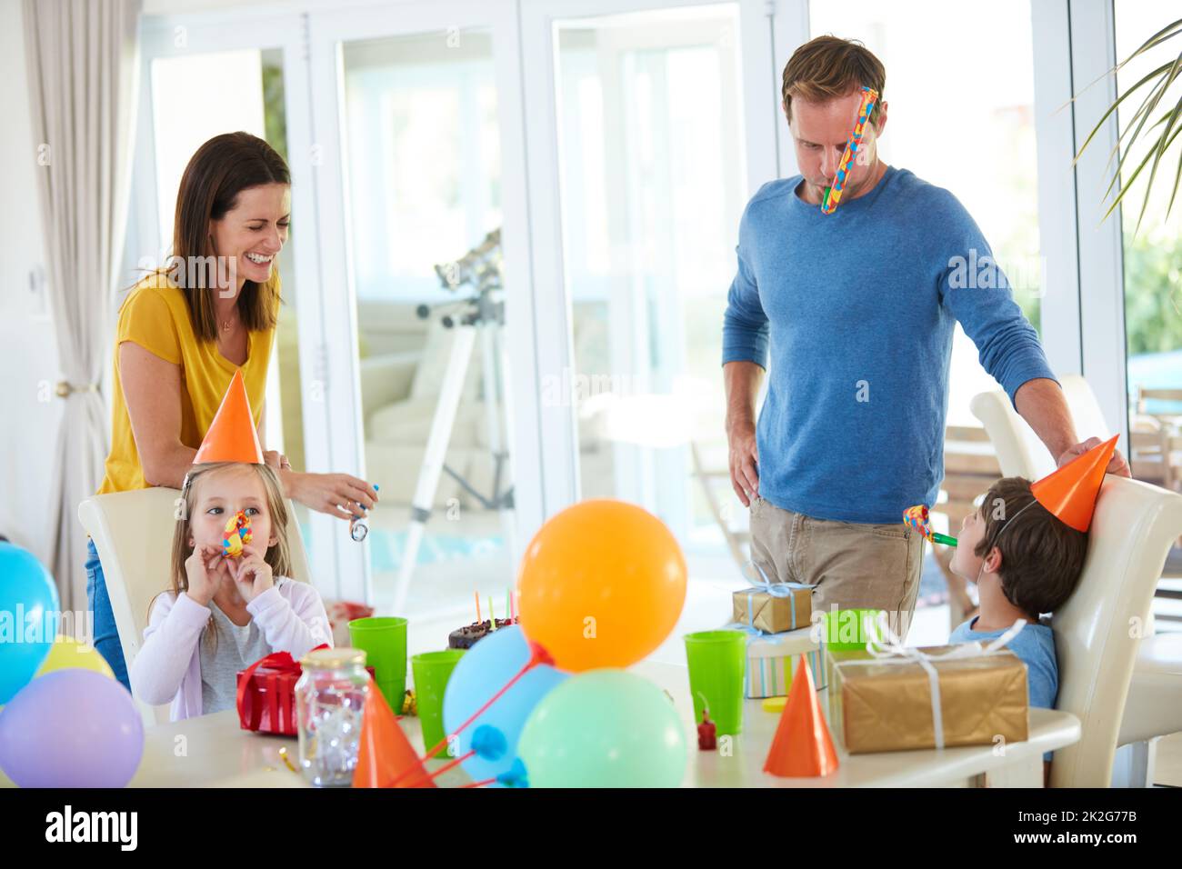 Festa di compleanno divertimento in pieno swing. Scatto di una famiglia felice che gioca con le corna del partito ad una festa di compleanno. Foto Stock
