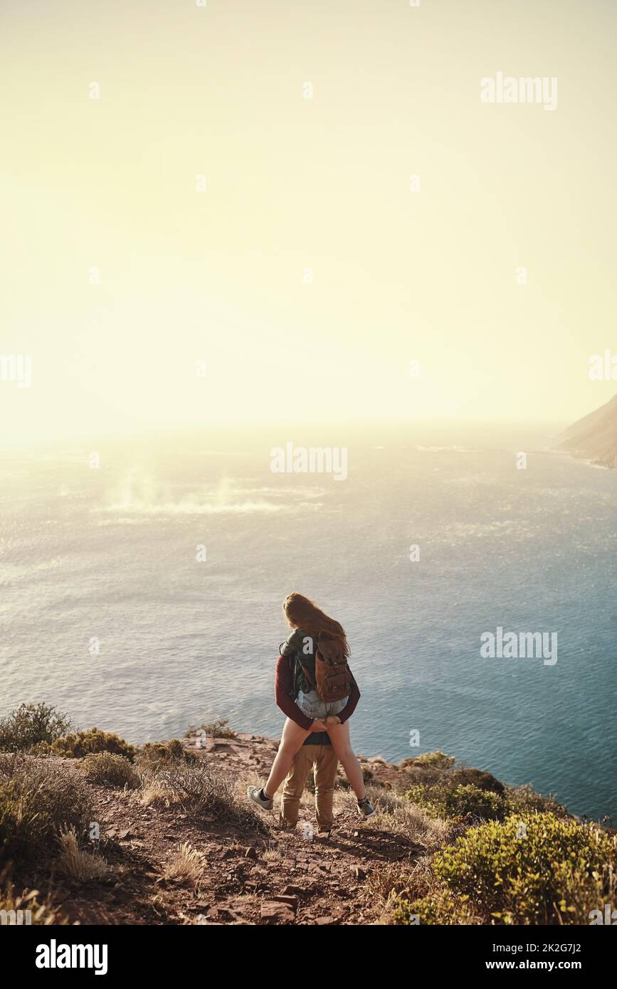Potete vedere da dietro là. Dietro l'immagine di un giovane uomo che sostiene la sua ragazza durante la loro escursione in montagna. Foto Stock