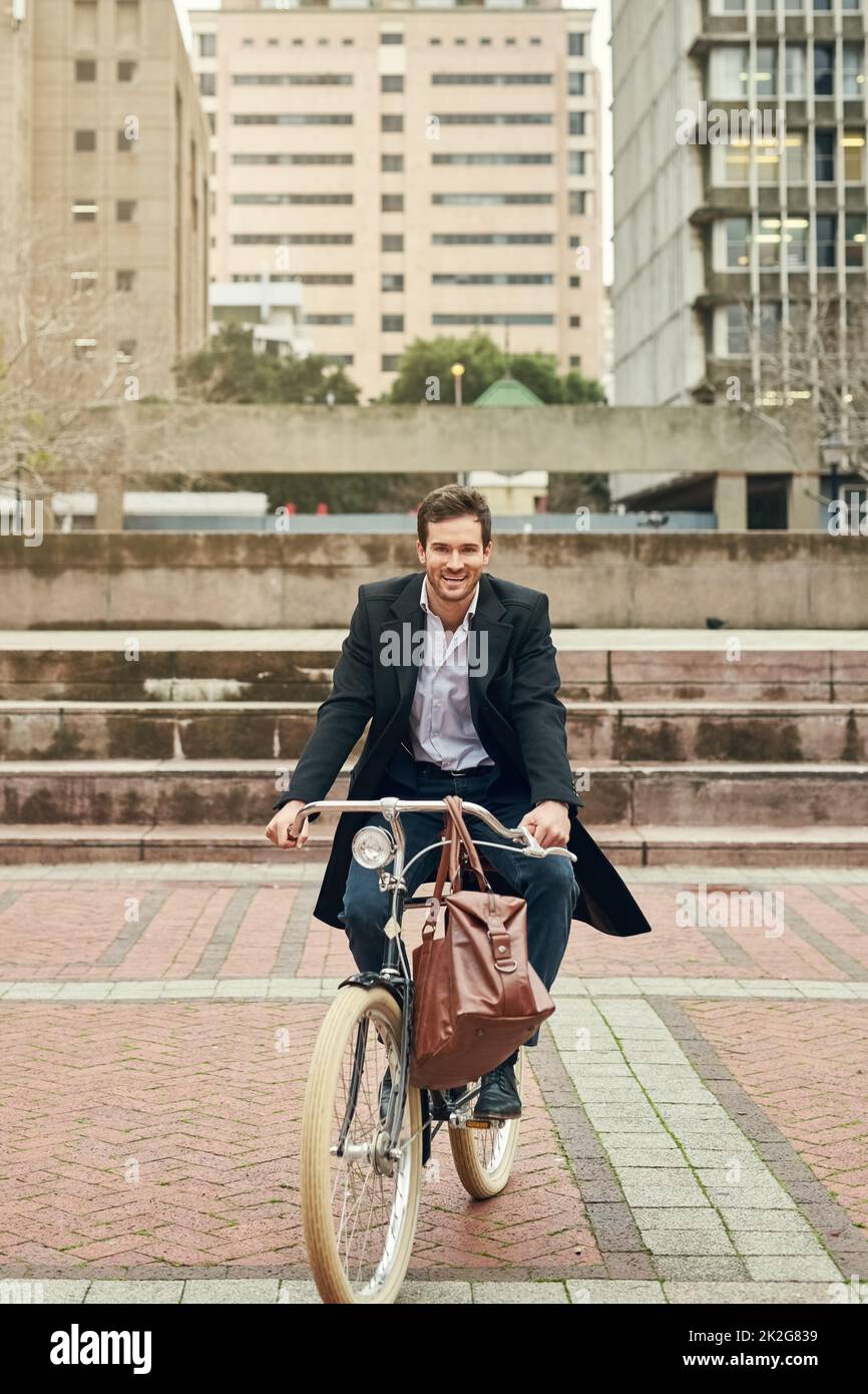 Pedalando attraverso una città di grandi possibilità. Ritratto di un giovane uomo d'affari che viaggia per lavorare con la sua bicicletta. Foto Stock