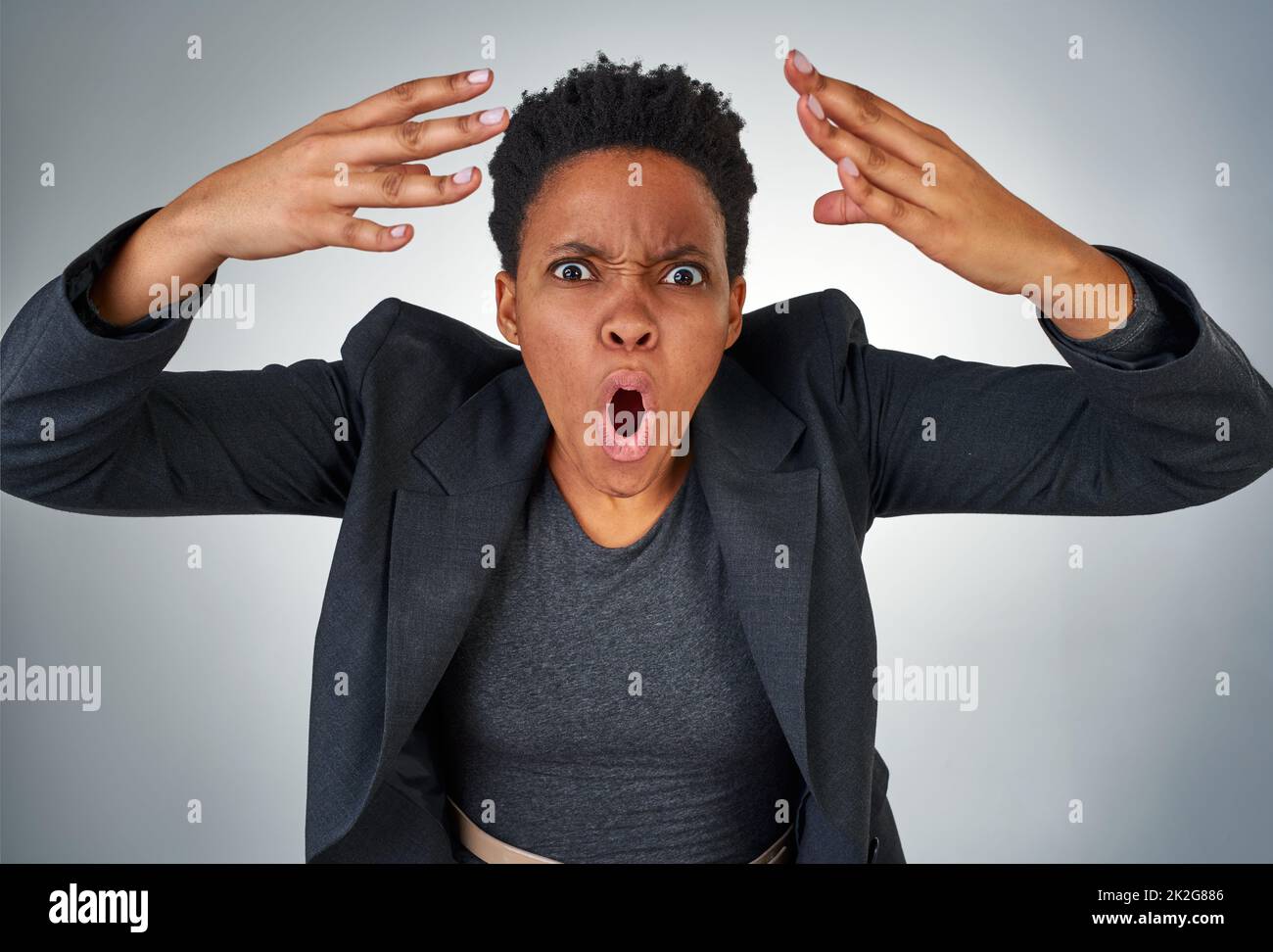 Che cosa pensavi. Ritratto di una donna d'affari arrabbiata urlando su uno sfondo grigio. Foto Stock