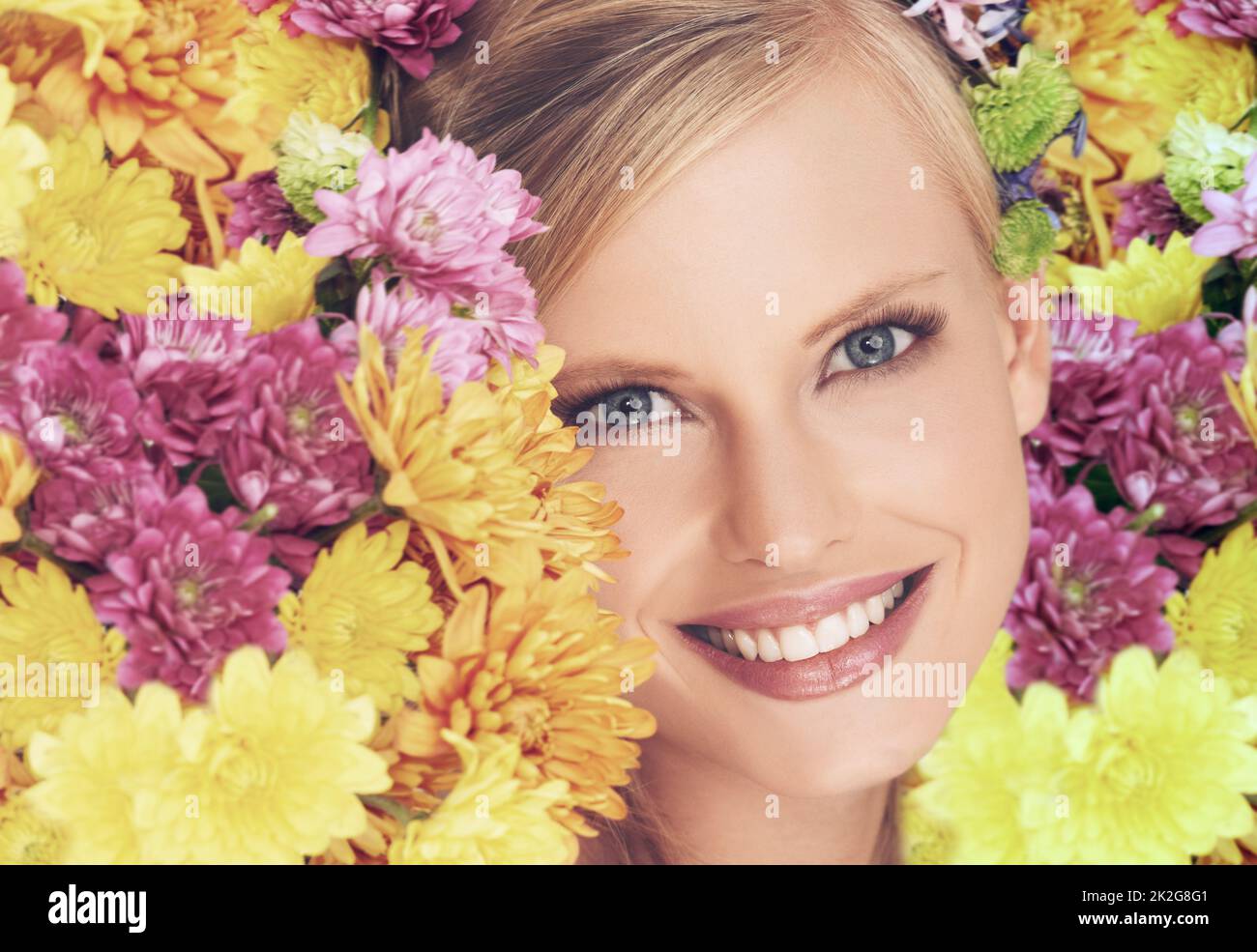 La sua bellezza non ha eguali. Una giovane donna con una disposizione di fiori nei suoi capelli sorridendo alla macchina fotografica. Foto Stock