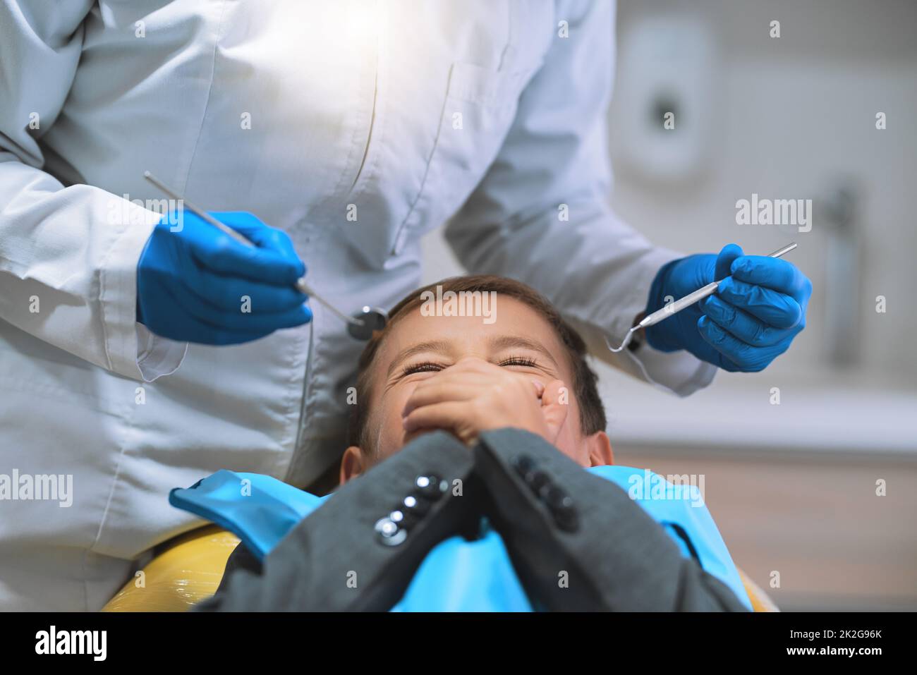 Im a spaventato per aprire la mia bocca. Colpo di un ragazzino spaventato sdraiato su una sedia da dentista e tiene chiusa la bocca per impedire al dentista di lavorargli. Foto Stock