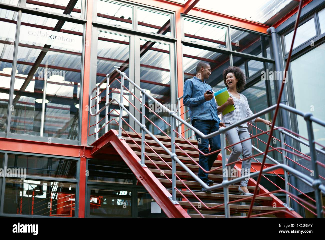 La comunicazione è la chiave del successo. Due colleghi camminano fianco a fianco giù per le scale nel loro edificio. Foto Stock