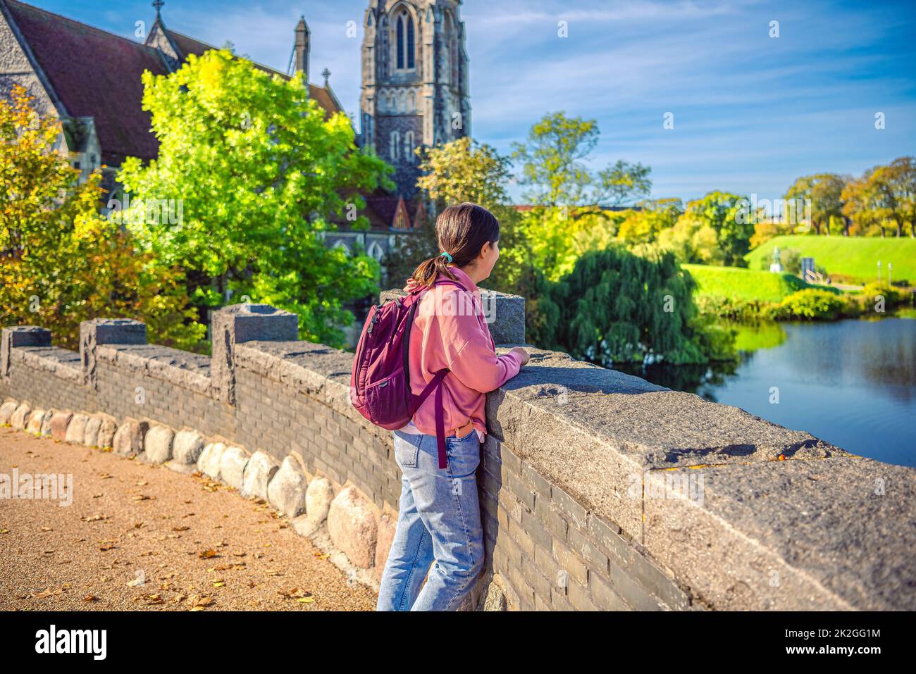 Una ragazza dai capelli neri guarda l'acqua nel lago vicino alla chiesa di San Albans. Copenaghen, Danimarca Foto Stock