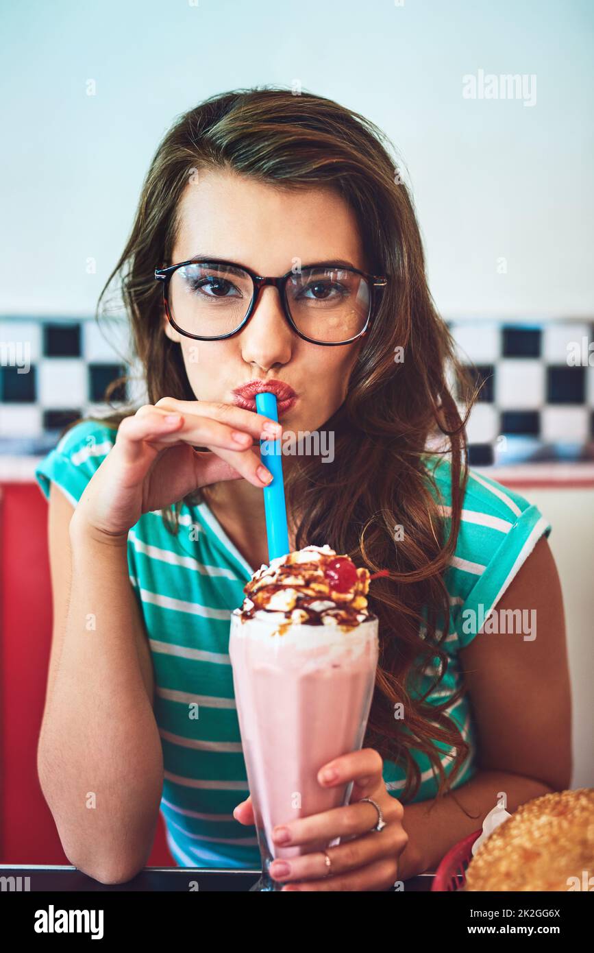 Scuotetelo. Ritratto corto di una giovane donna attraente godendo un milkshake in una cena retrò. Foto Stock