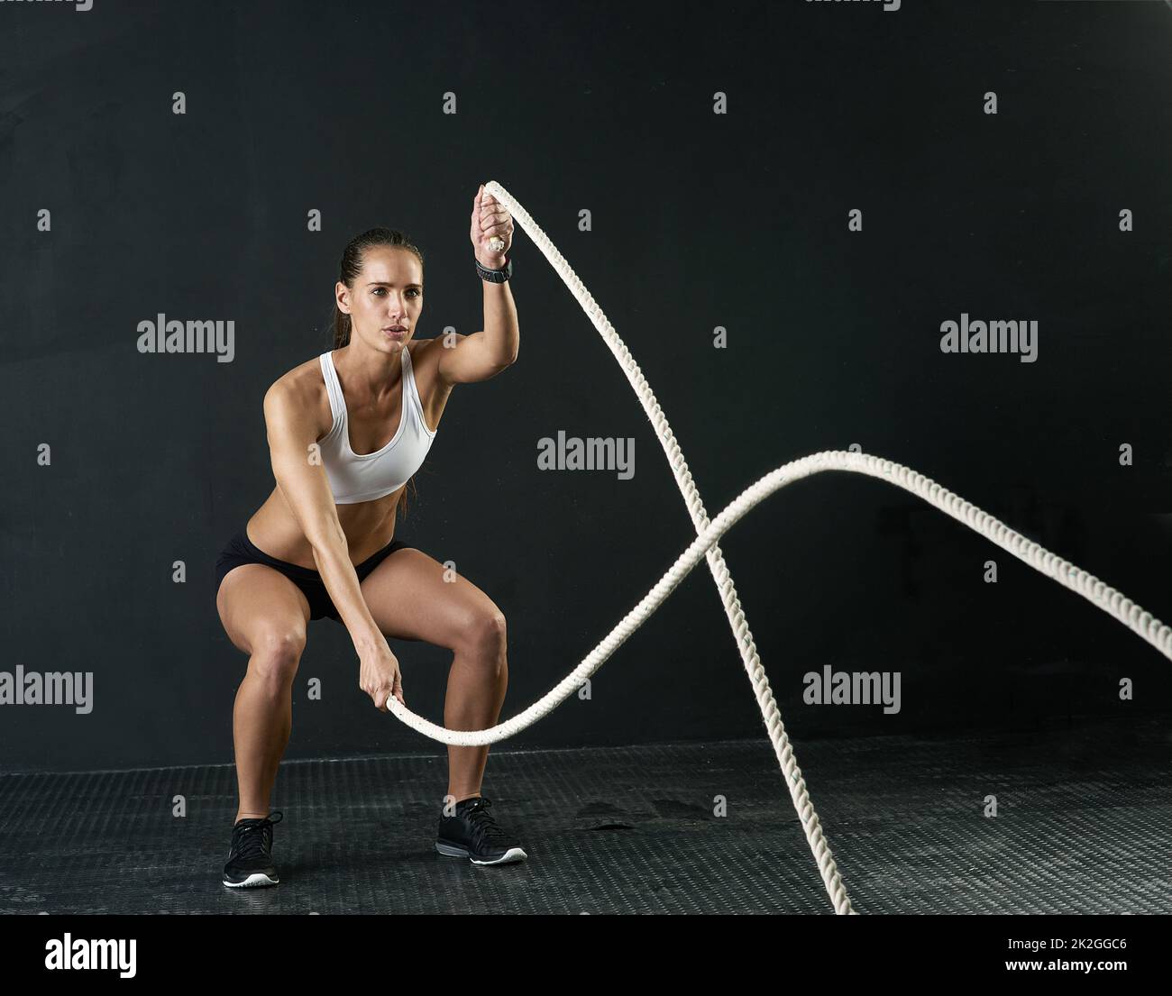 Queste corde sono davvero una battaglia. Studio girato di una giovane donna attraente che si sta allenando con corde pesanti su uno sfondo scuro. Foto Stock