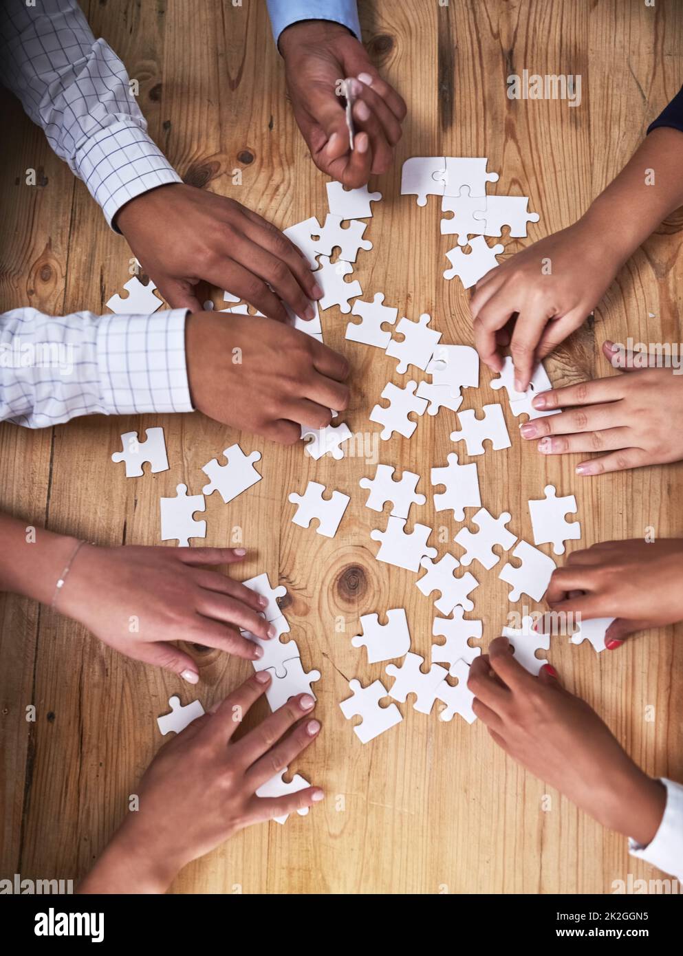 Questo team non è facilmente perplesso. Colpo ad angolo alto di un gruppo di uomini d'affari non identificabili che costruiscono insieme un puzzle in ufficio. Foto Stock