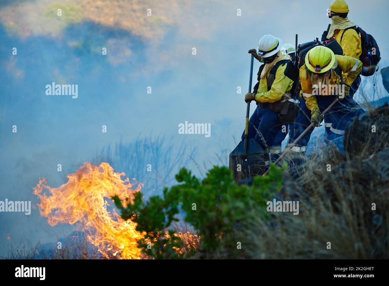 Dove i theres fumano, i theres sparano ed i combattenti del fuoco. Colpo di vigili del fuoco che combatte un fuoco selvaggio. Foto Stock