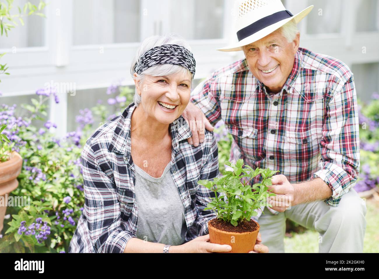 L'aria fresca e la bellezza della natura ci tengono giovani. Una coppia anziana felice di giardinaggio occupato nel loro cortile posteriore. Foto Stock