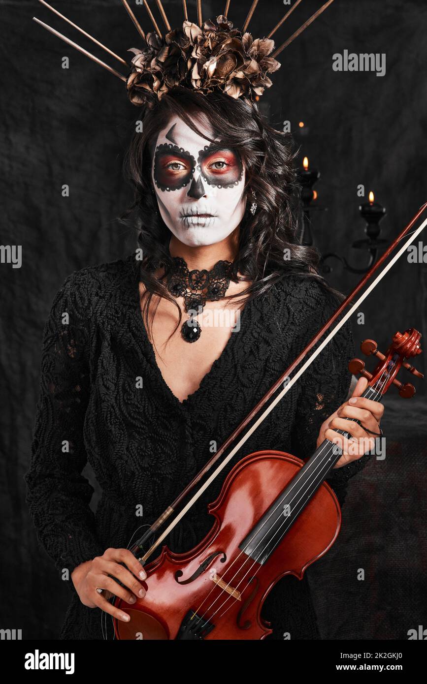 Halloween isnt completo senza musica. Ritratto corto di una giovane donna attraente vestito con il suo costume messicano di Halloween che suona un violino. Foto Stock